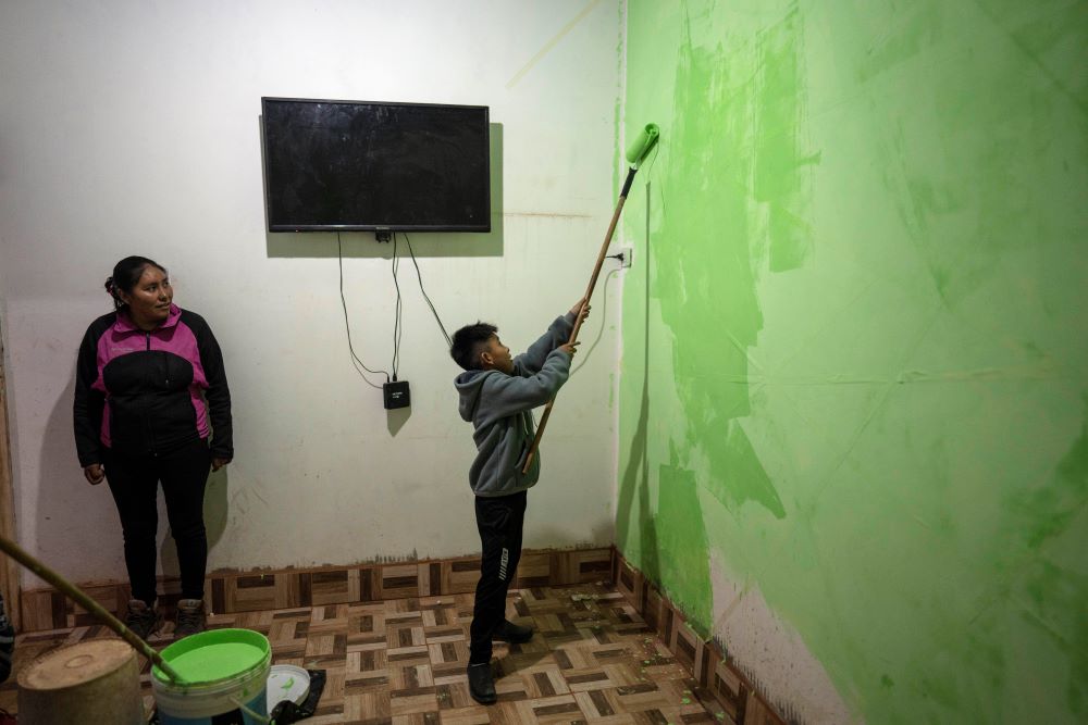 Elizabeth Mamani, 30, watches her son, Alexis, 10, paint the walls of their new house in Huancar, Jujuy Province, Argentina, on April 25, 2023. The Andean town is prospering because of the work available in nearby lithium mines.